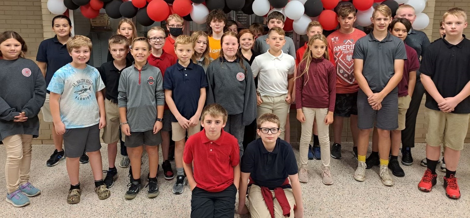 Members of the JMS Robotics Club pose in front of trophy cabinet in school entryway.