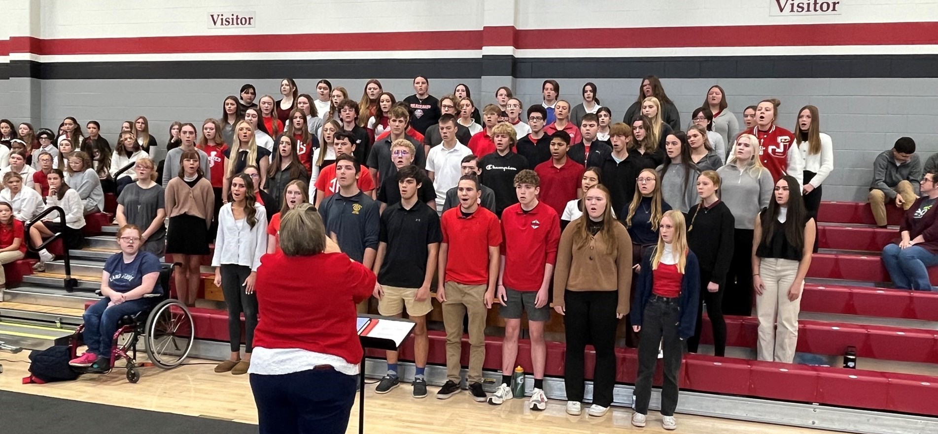 Choir members stand on bleachers and perform songs for veterans