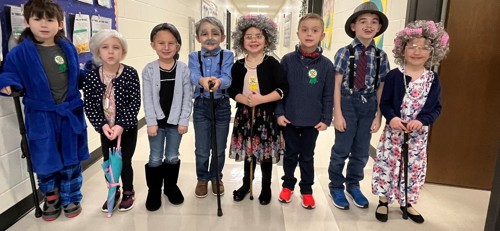 Elementary students standing in hallway, are costumed as senior citizens