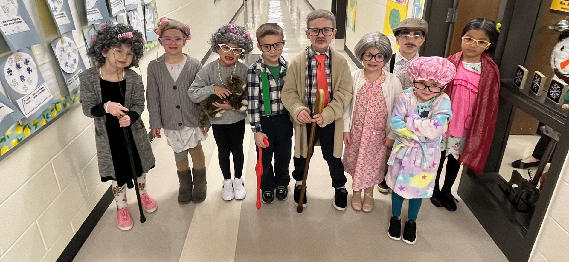 Elementary students standing in hallway, are costumed as senior citizens
