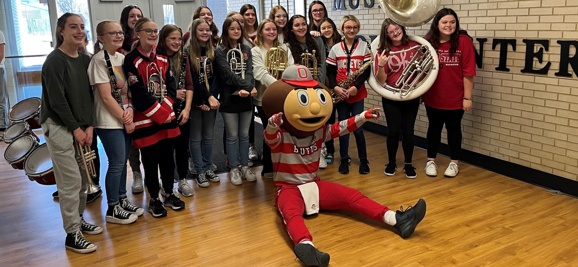 Costumed OSU Mascot Brutus Buckeye seated before Middle School Band members