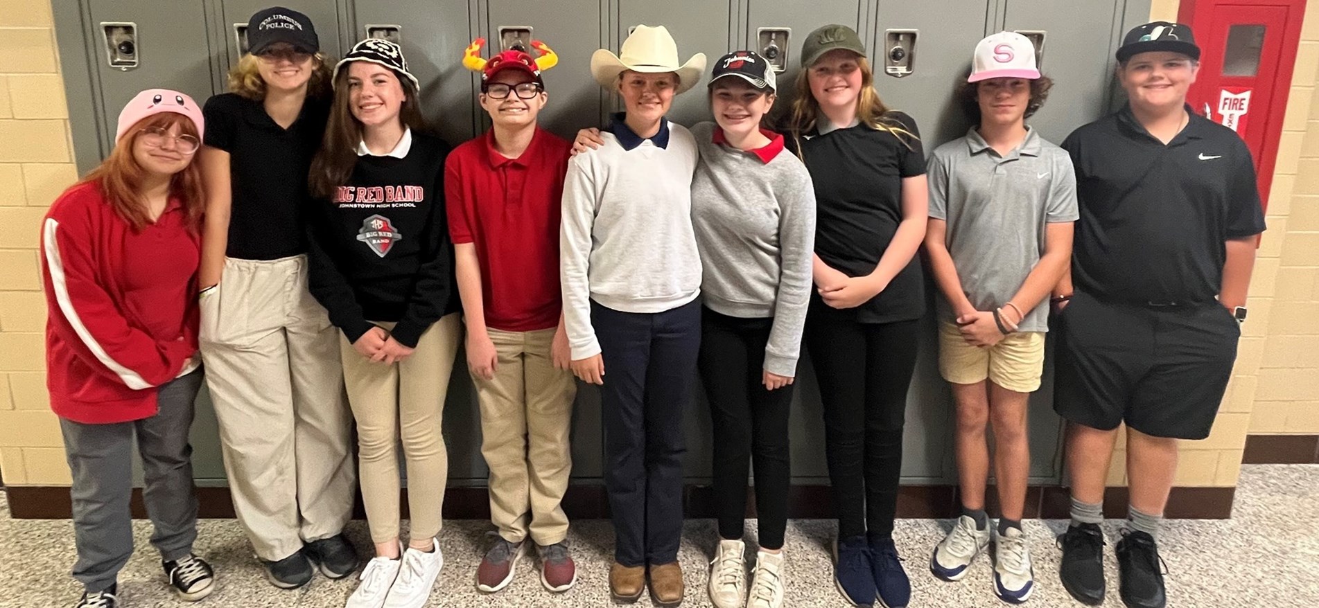 Students stand before lockers wearing hats for special spirit wear day
