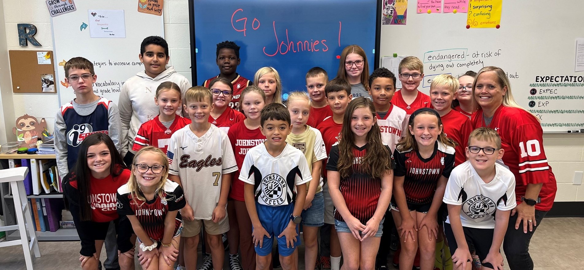 Students and teacher gather for photo wearing sports jerseys for Spirit Week.