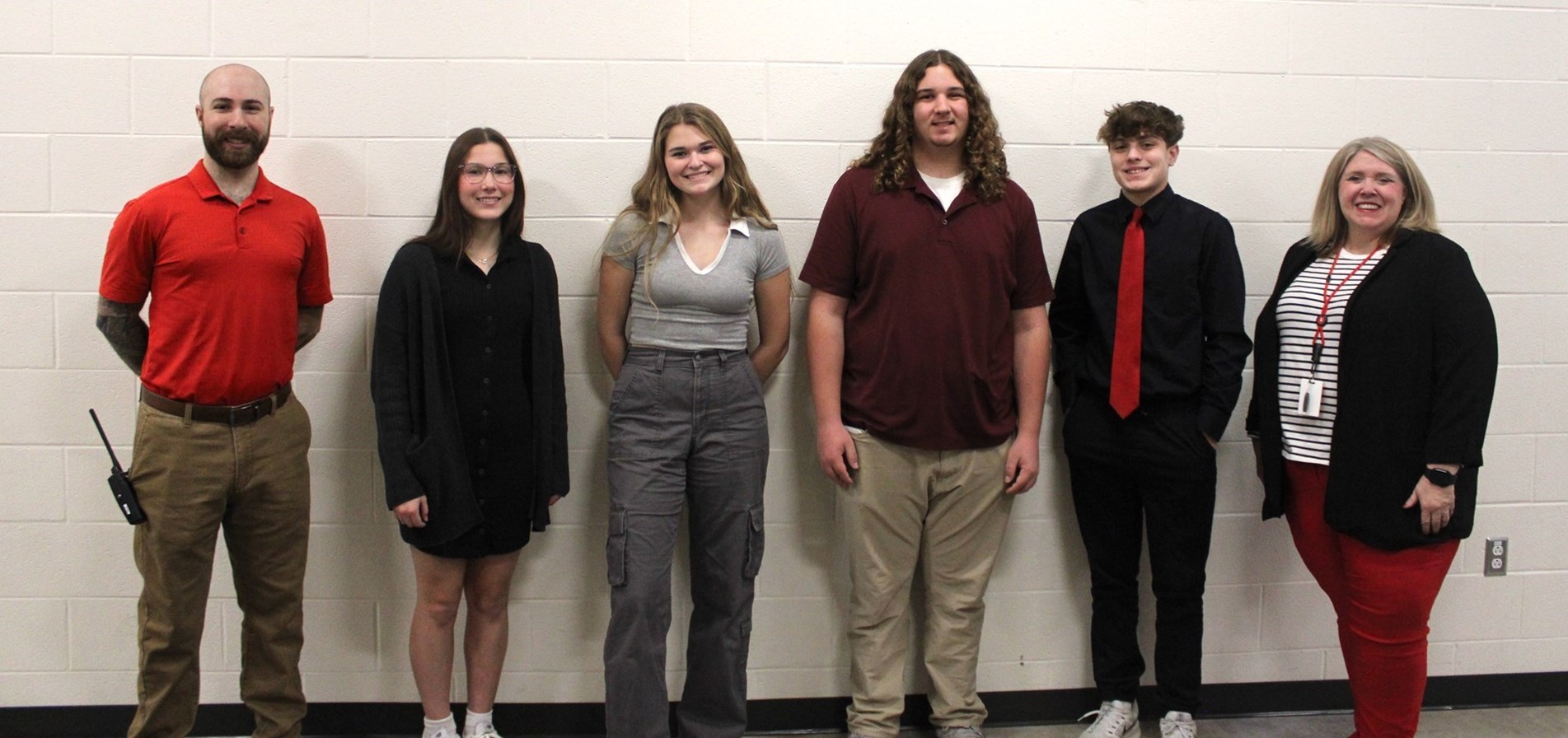 JHS students of the month and administrators stand before white brick wall.