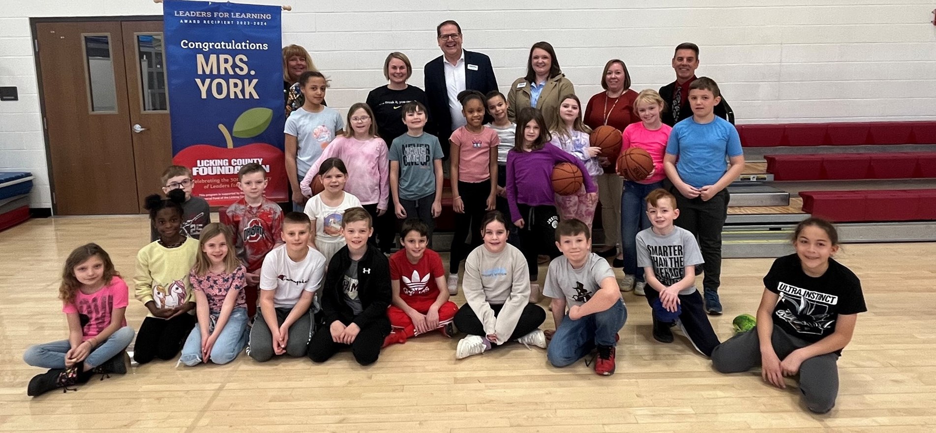Leaders for Learning Award-Winner Megan York is surrounded by Licking County Foundation, students and District administrators in elementary school gym.