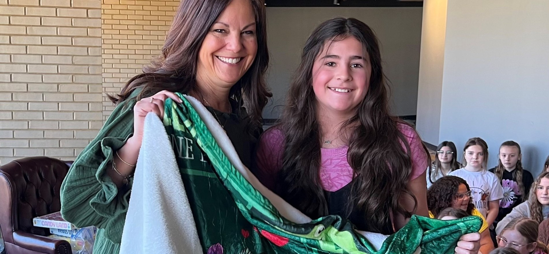 Instructor and student hold blanket during special blanket, boardgame and books event