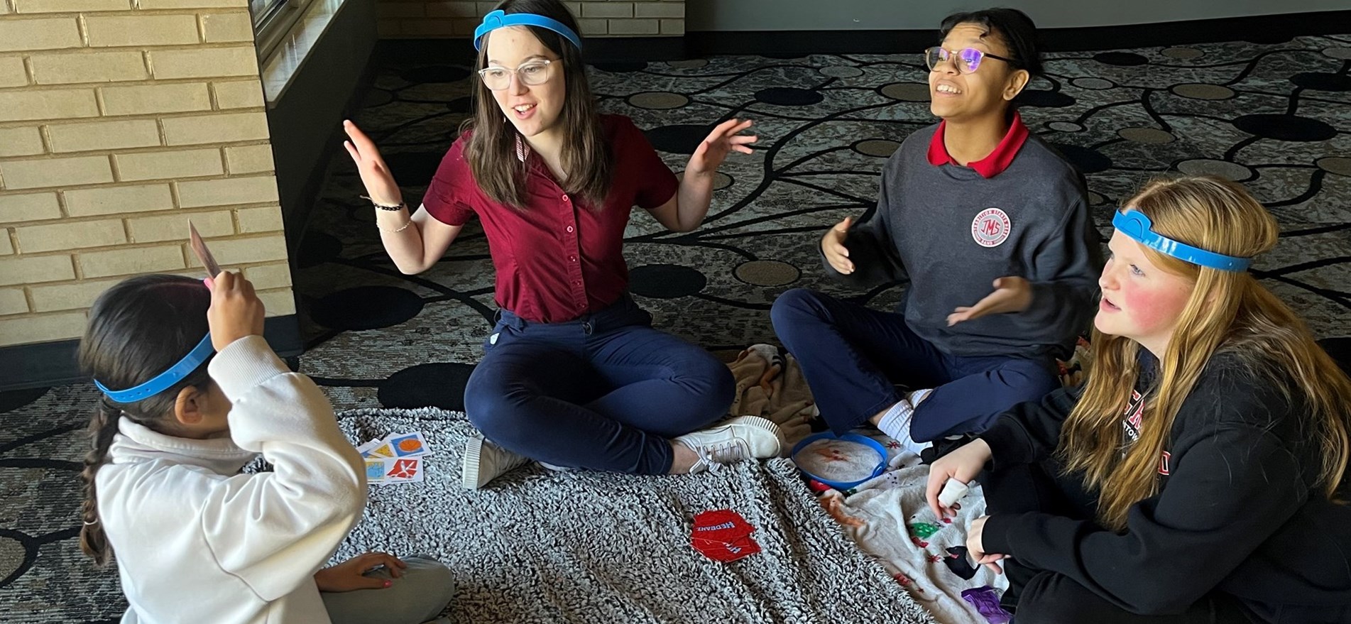 Students sitting on blankets on floor play board games.